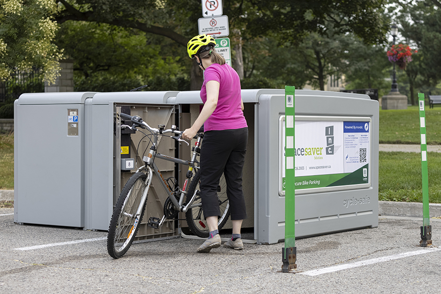 A woman with a bike uses the bike lockers in London