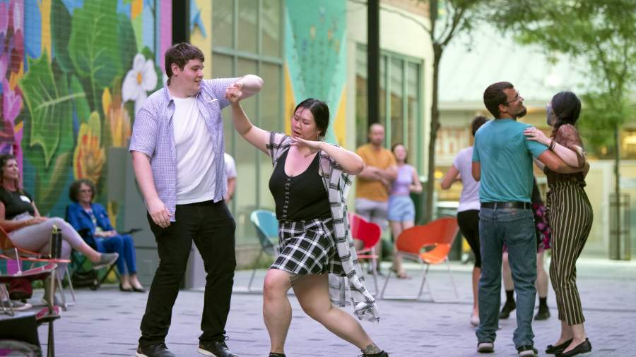 Two people dance together on Dundas Place in Market Lane